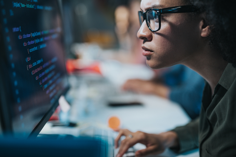 young woman examining code on computer