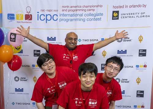 instructor and smiling CIS students in front of ICPC banner
