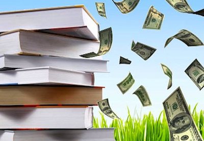 stack of books on grass with dollar bills fluttering in the air