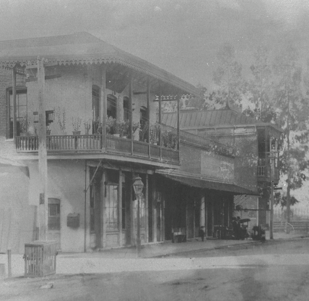 View of Heinlenville circa 1900, with the Ng Shing Gung temple on the far right. Photo courtesy of The Californian, Number 43, Oct 2016. A black and white photograph depicting buildings on a tree-lined street, with Chinese-style facades and balconies