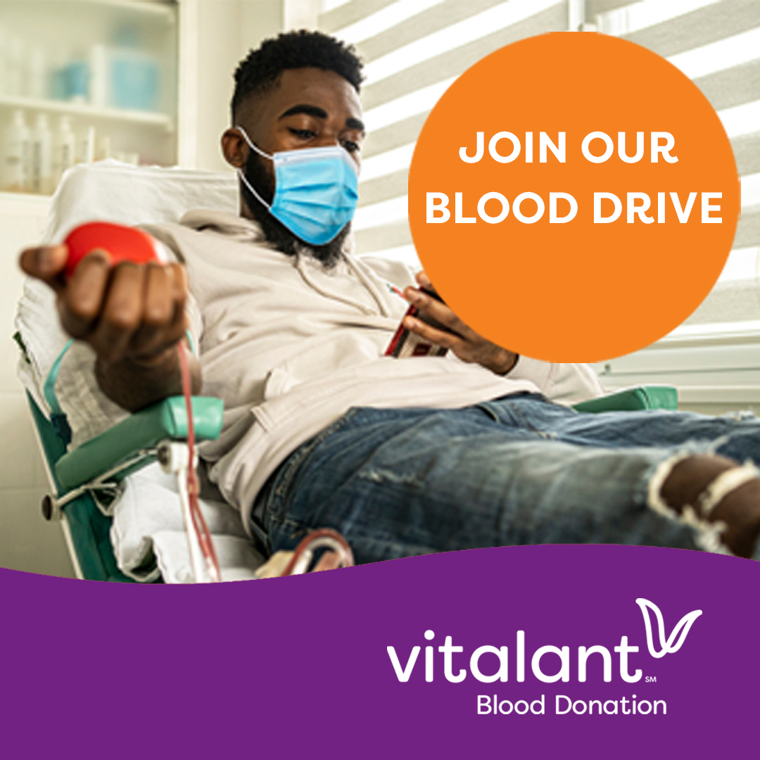 Young African American man wearing a face mask and reclining on a seat while squeezing a stress ball as he prepares to donate blood. There is text in an orange circle on the right side that reads "Join our Blood Drive" and the Vitalant logo is at the bottom of the image in a purple wavy border