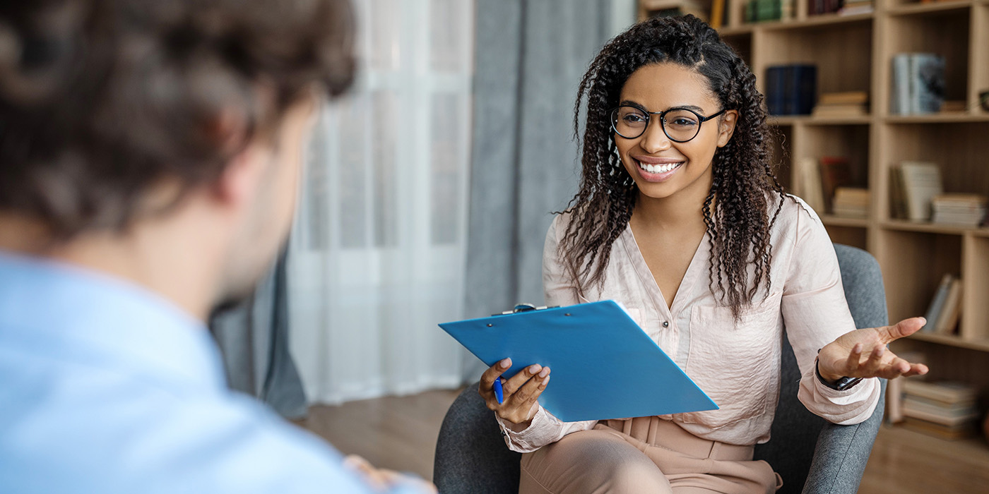 woman with file in hand speaking with another person in an office