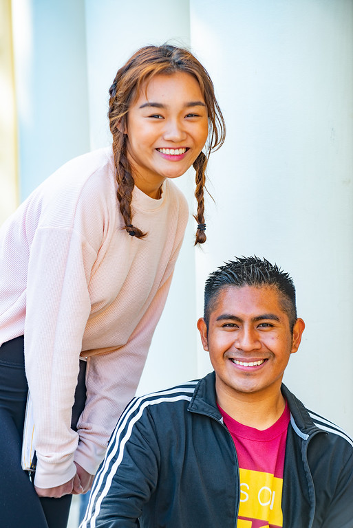 young woman standing and smiling, young man seated