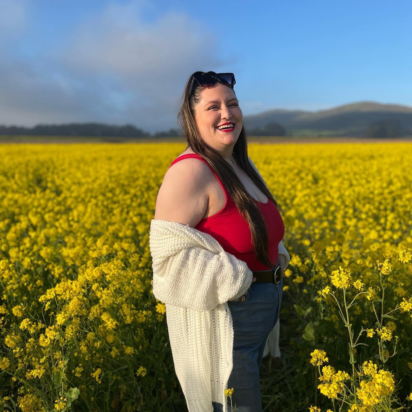 Mia Hernandez facing the camera satnding in the middle of a field of flowers.