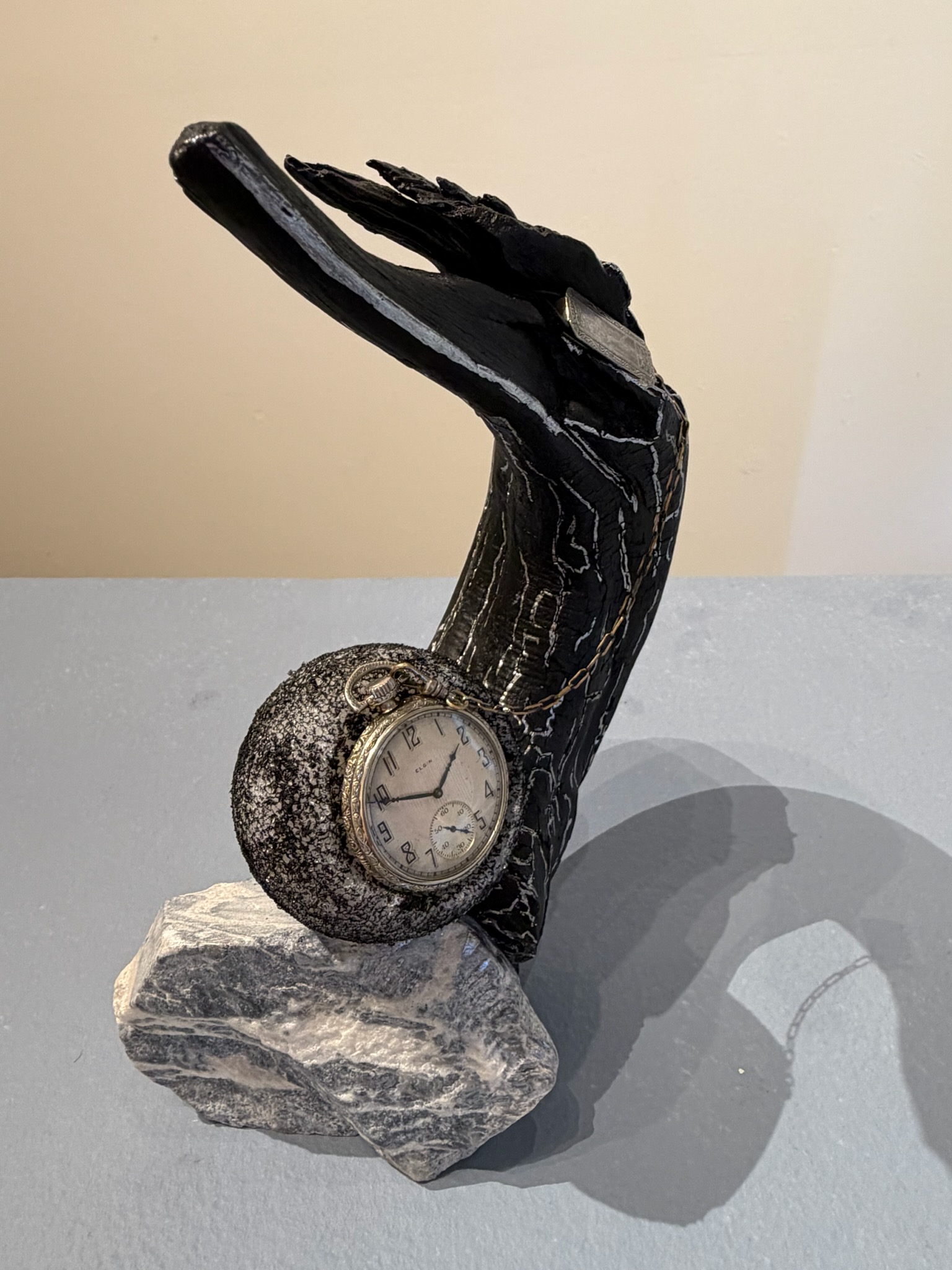 marble sculpture of a bird on a tree branch with a watch embedded below