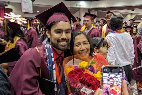 smiling young man in grad cap with mom and flowers