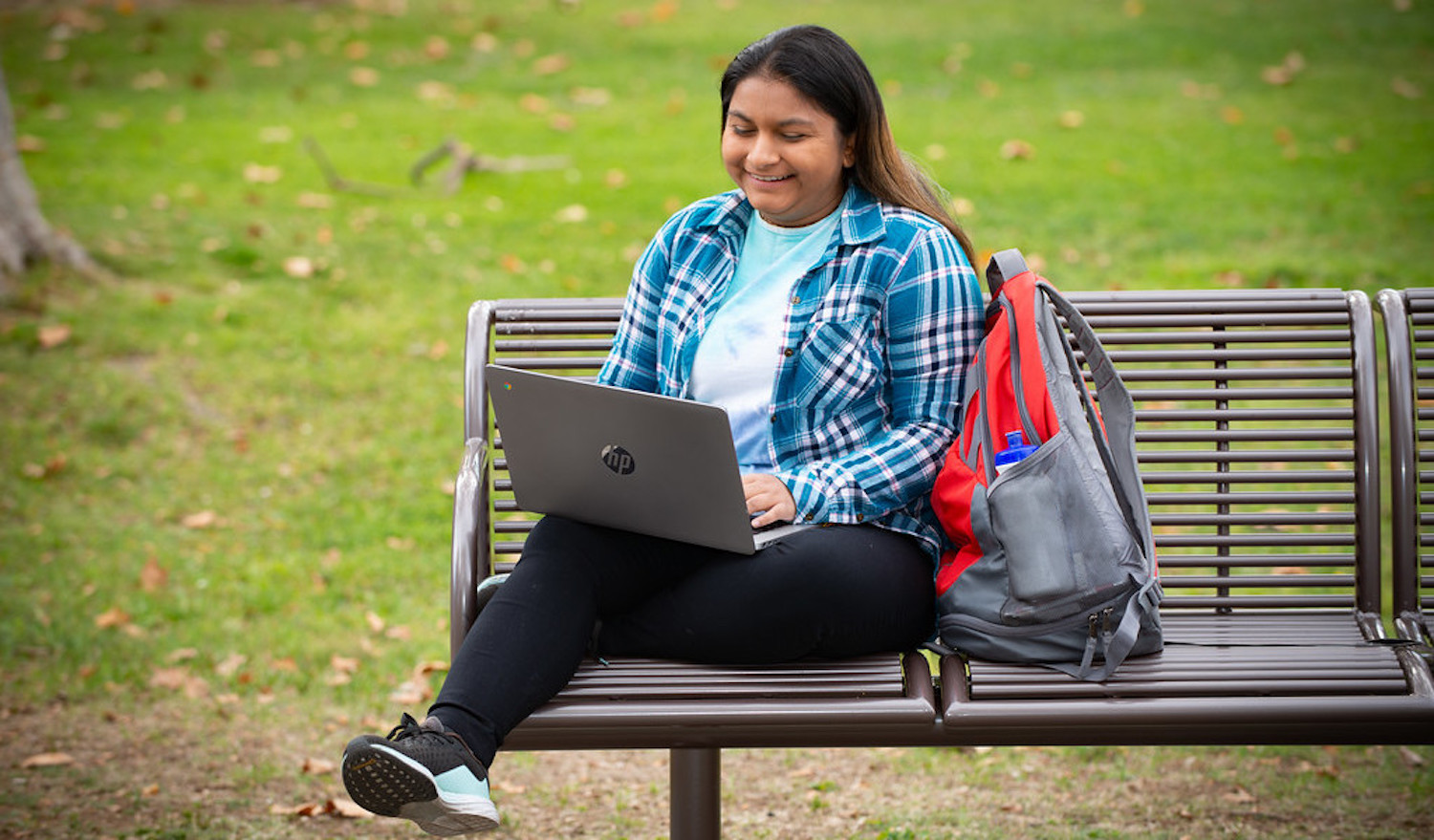 young woman with laptop on bench outside