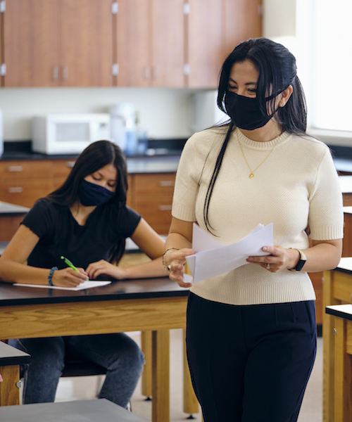 teacher with student, both wearing masks