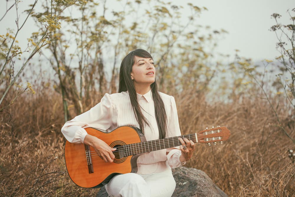 Diana Gameros: woman in white dress playing guitar