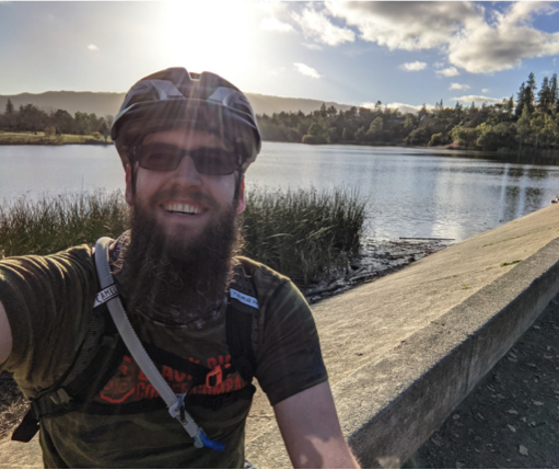 smiling Max Knudsen in bike helmet by lake